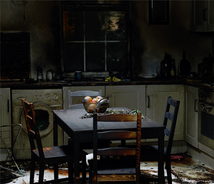 a fire damaged kitchen with soot covering the dining set and counters